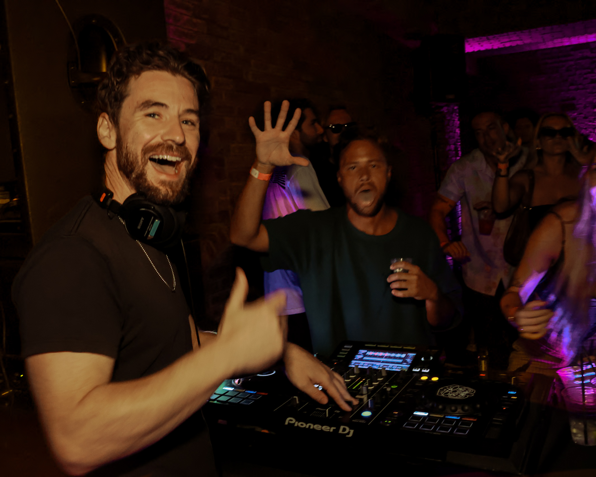 DJ at indoor venue, pink lights, crowd